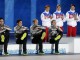 Золотые медалисты из России стоя аплодируют команде из США, выигравшей серебро в шорт-трек в 5000-метровой эстафете, сидящим на подиуме, во время церемонии награждения в Сочи. 